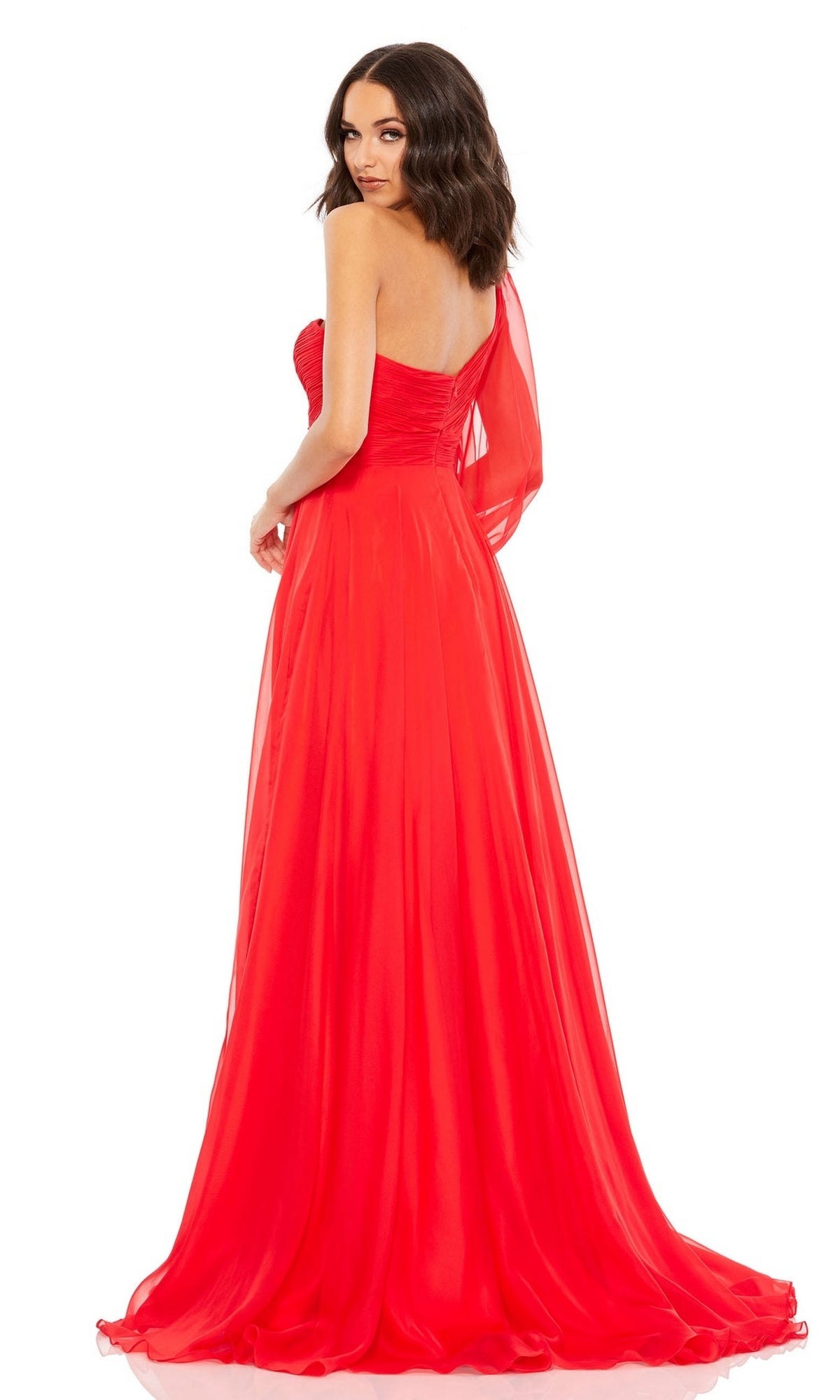 A woman poses against a plain white background in a Mac Duggal 67810 one-sleeve long red formal dress, glancing over her shoulder.